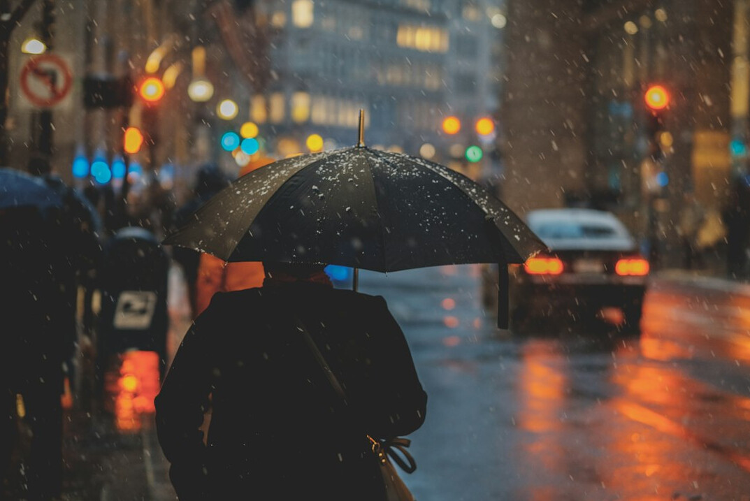 Woman holding an umbrella while waiting in line in the rain