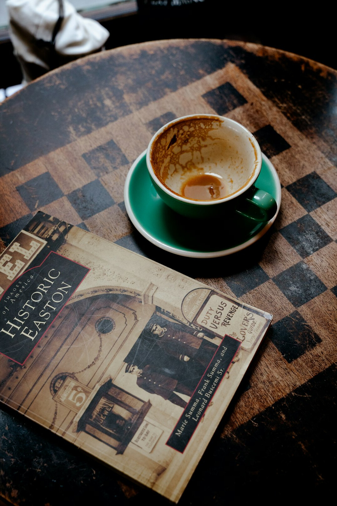 A hardcover photo book lying open on a wooden table next to a cup of coffee