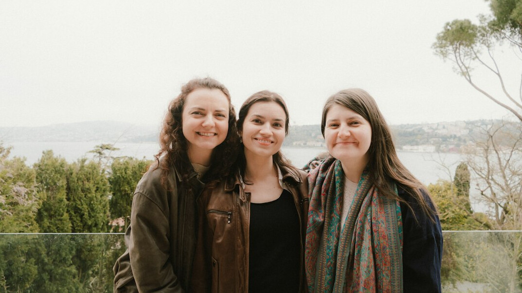 A small team of three colleagues standing together and smiling